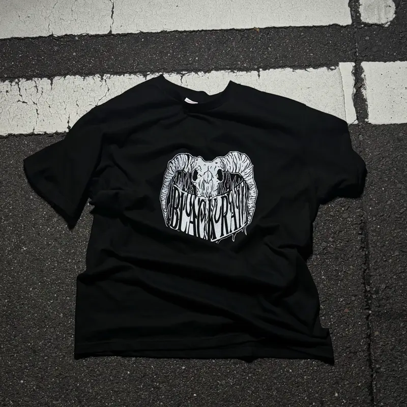 地面に置かれた黒いTシャツ。胸に白いグラフィック