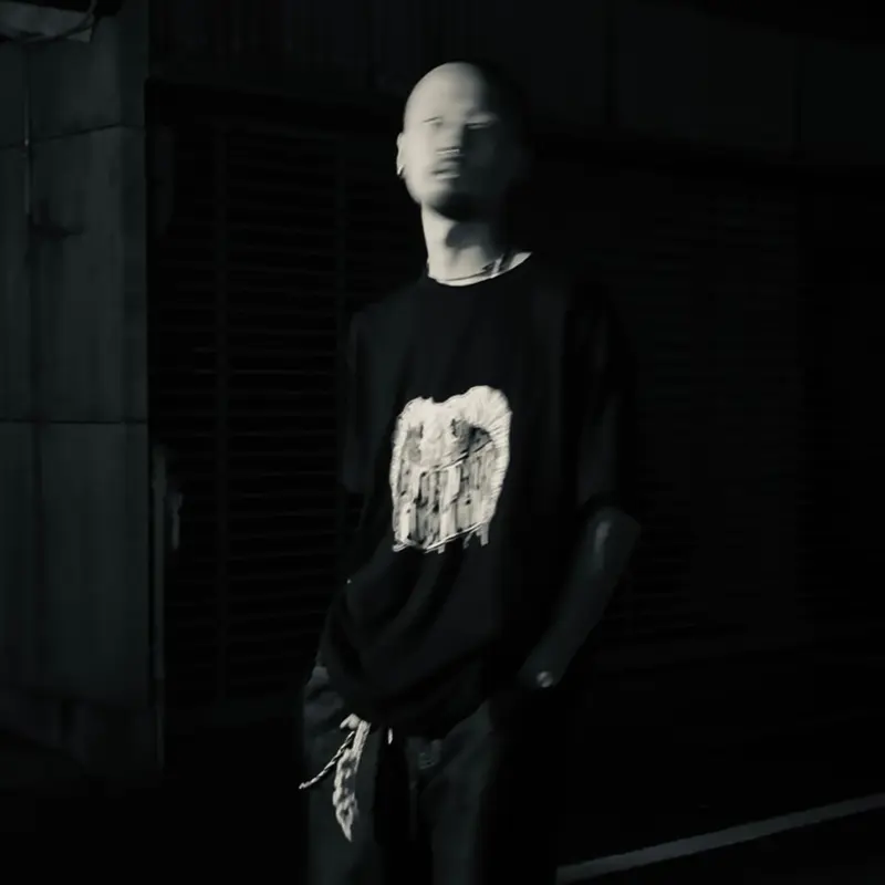 暗がりでTシャツを着て立つメンバー