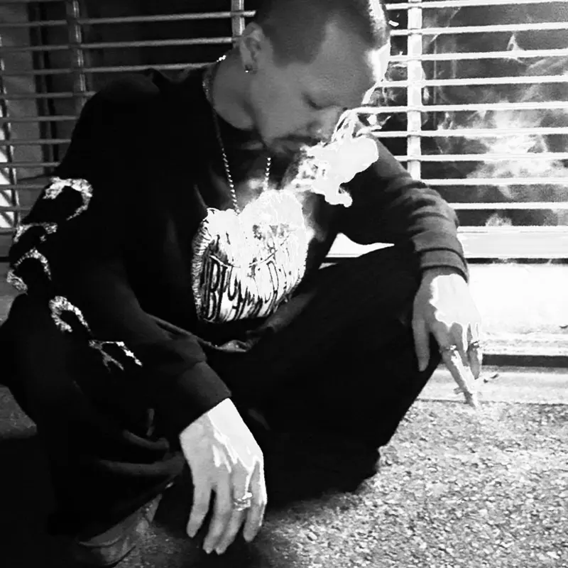 モノクロ写真。Tシャツを着てしゃがむメンバー